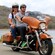 A couple rides a Harley Davidson motorcycle